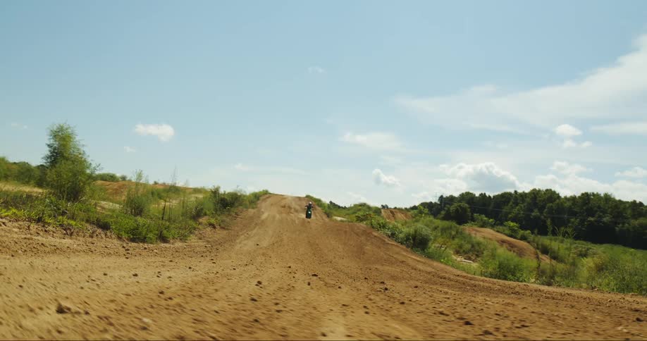 Motorcyclist rides motocross course near woods on cloudy day