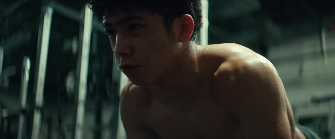 A man without a shirt on doing push ups on the floor and sweating
