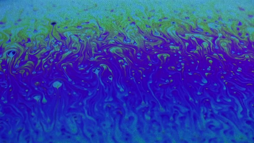 Bright blue and purple liquid flows to the right and creates little swirls all over