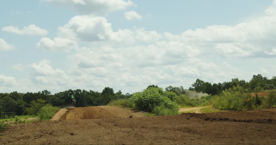 A motocross rider jumps over a dirt hill