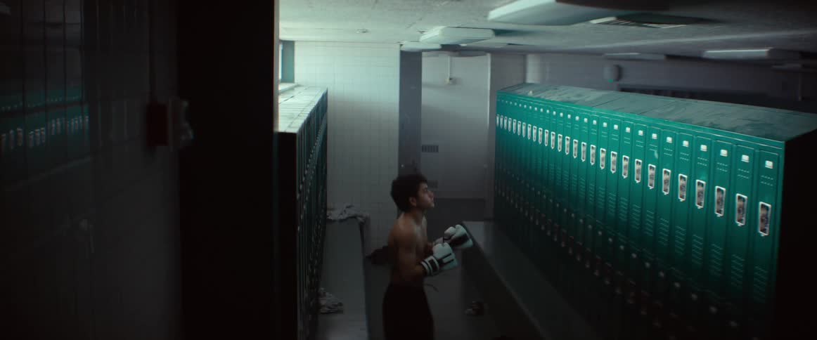 Boxer wearing gloves shadowboxes while standing in locker room