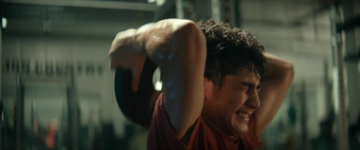 An up close of a man lifting weights over the back of his head