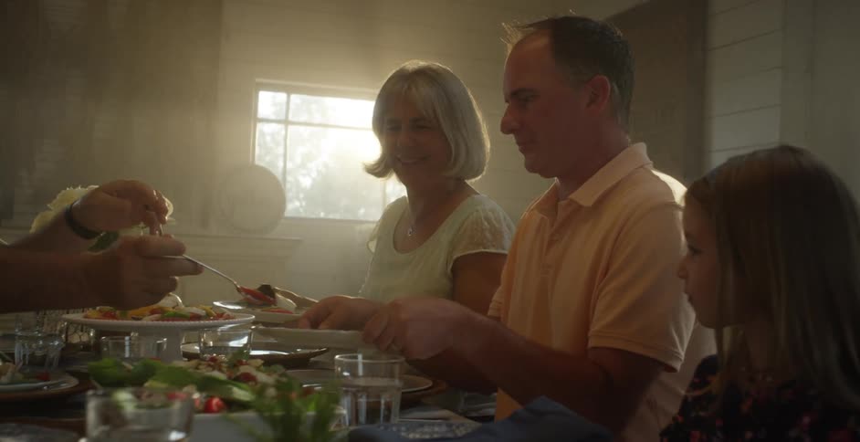 Man holds his plate up at family dinner table to be served
