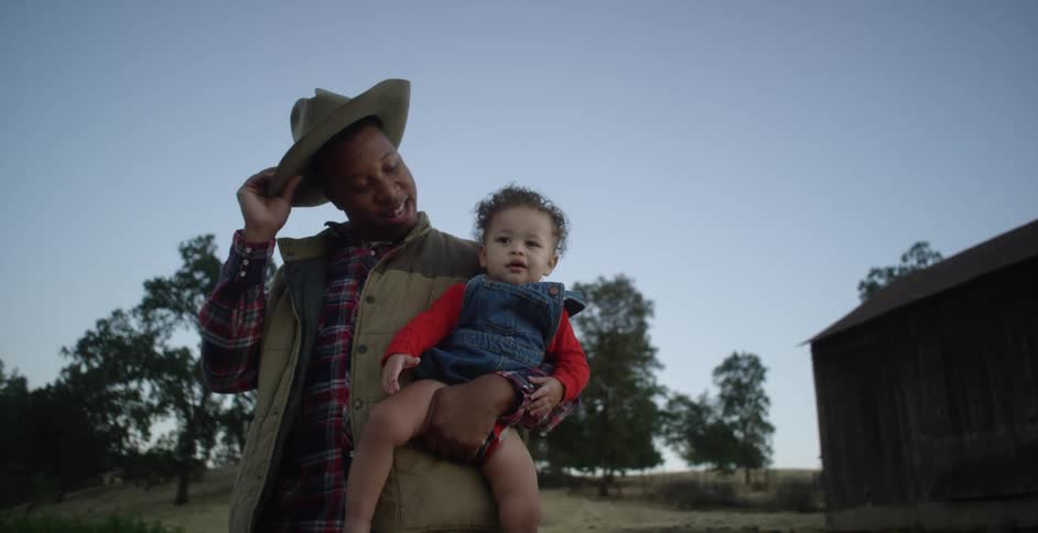A father takes off his cowboy hat and places it on his young sons head