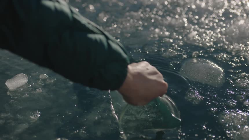 Man scoops up icy water with a beaker