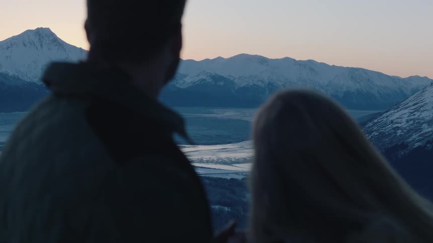 A man and woman are head to heat before turning to look at a view