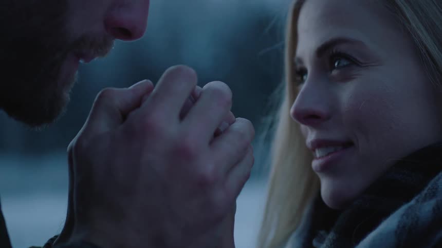A man blows on a woman's hands in the cold