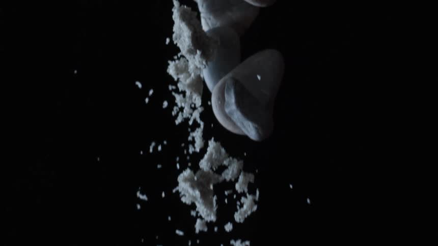 Slow motion sand and rocks thrown up into the air and then falling back down