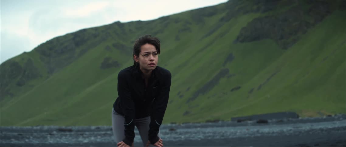 A woman leans forward by the mountains