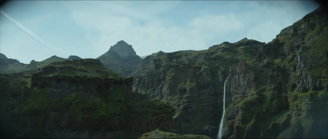 A waterfall crashes down a mountain range