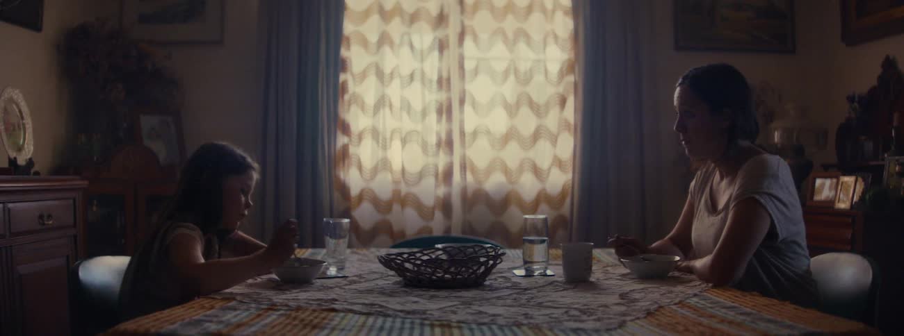 A mother and daughter dont speak while eating at their dining room table