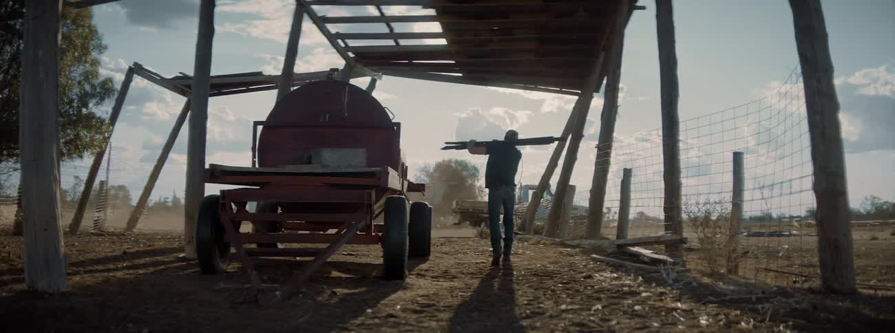 A man grabbing wood off a platform and walking away towards a truck