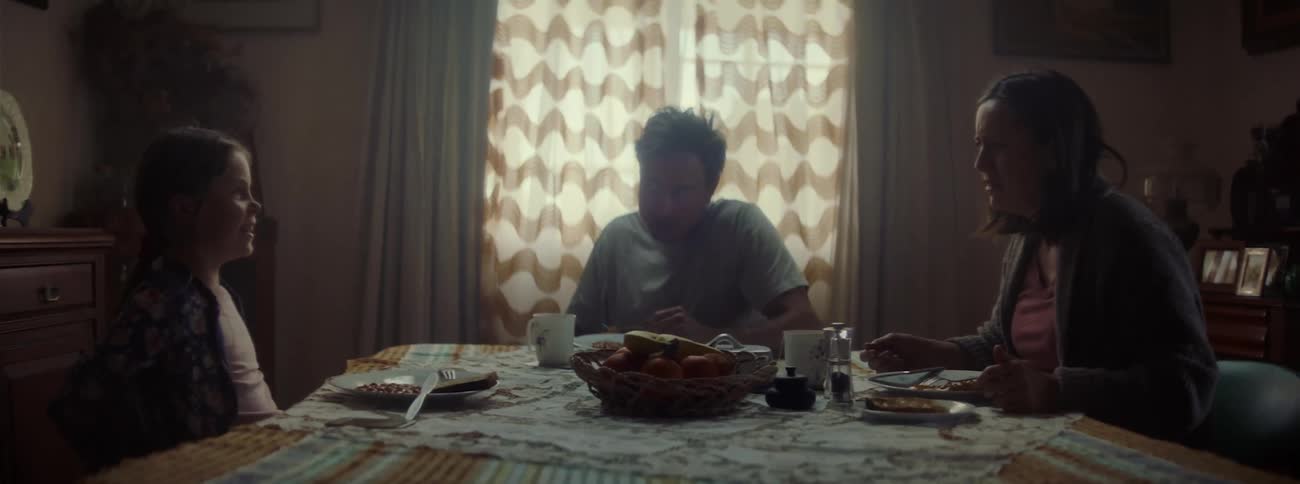 A young family chatting while eating a meal at the dinner table