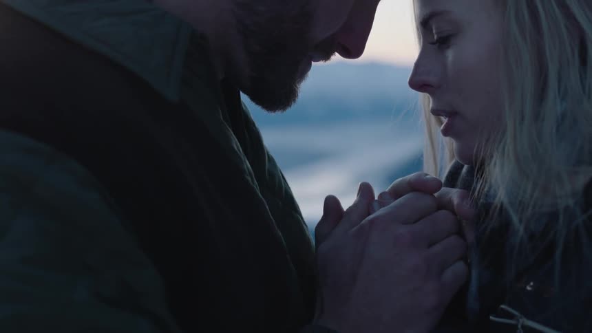 A man and woman hold hands and face each other