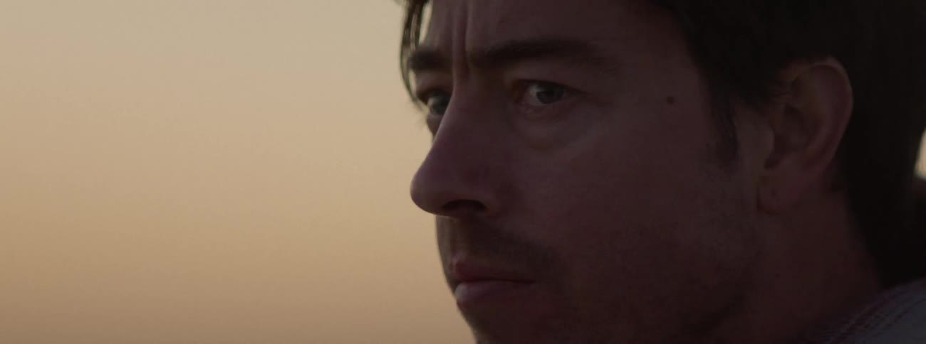 Wind blows through a mans hair while he looks at the horizon