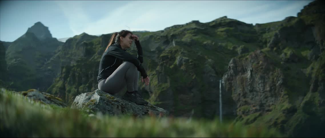 A woman sits on the rock by the mountain