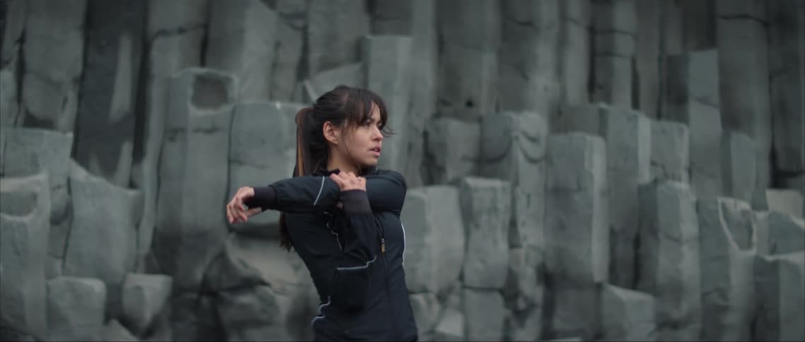 A woman stretching her arm next to a rock wall