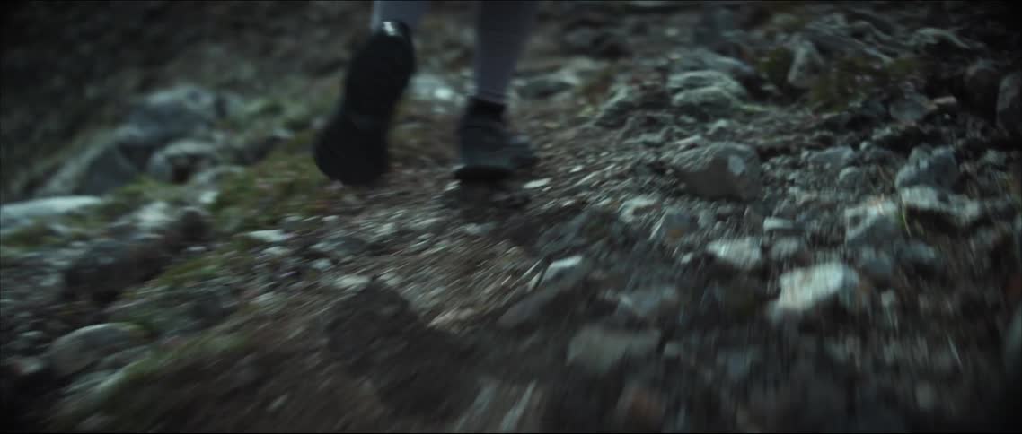 Person with black shoes and gray leggings runs up snowy hill