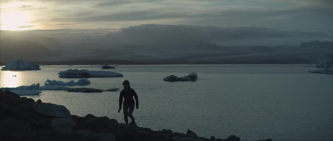 A woman stretching and jogging over rocky terrain in nature on a winter morning