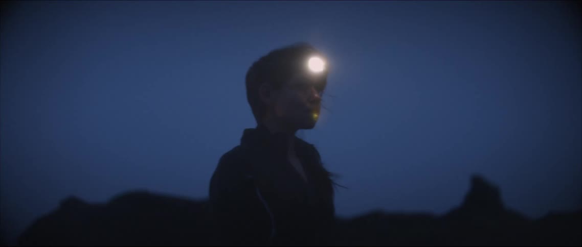 A womans silhouette standing with a head lamp on their face