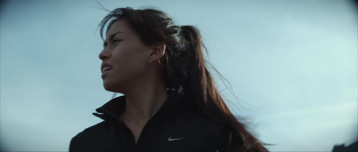 A woman raises her arms in excitement while running through a canyon