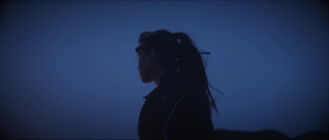 A woman is standing outside as the head lamp she is wearing glows as the darkness