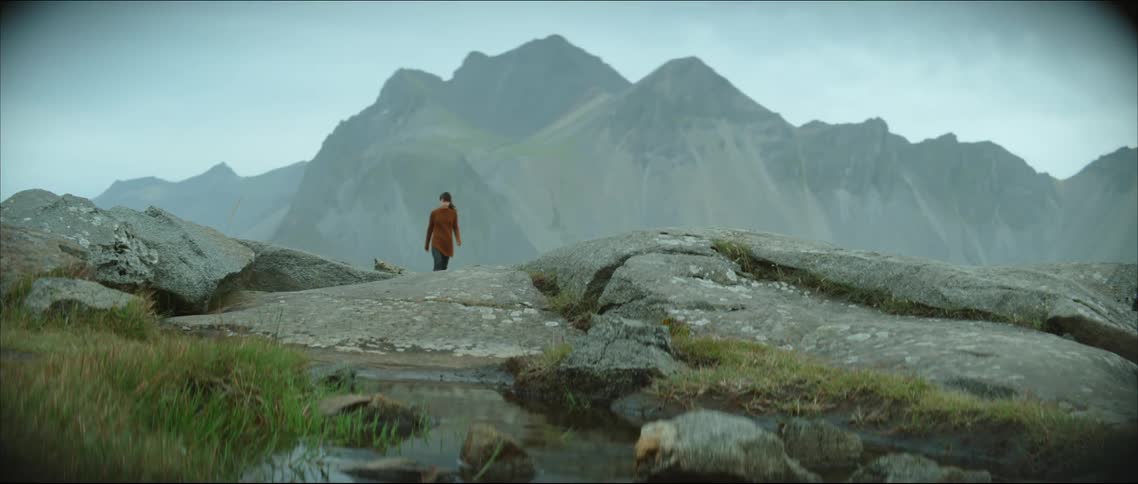 A woman walks toward a creek in a canyon