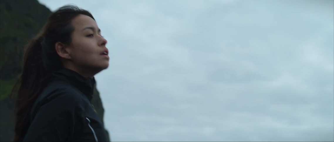 A woman standing on a coast line looking out into the water