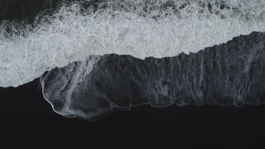 Waves splash and foam as they roll into shore and over the beach