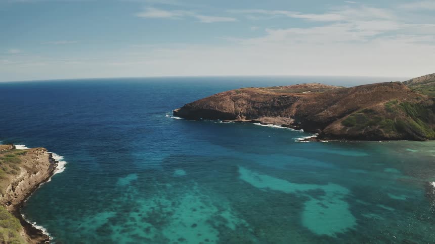 Waves splash against the coast as the seabed is seen through the clear water as waves roll into the shore of hanauma bay