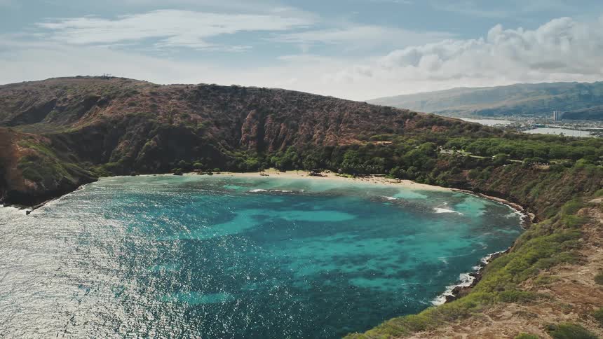 A coastal beach cove surrounded by mountains and vegetation