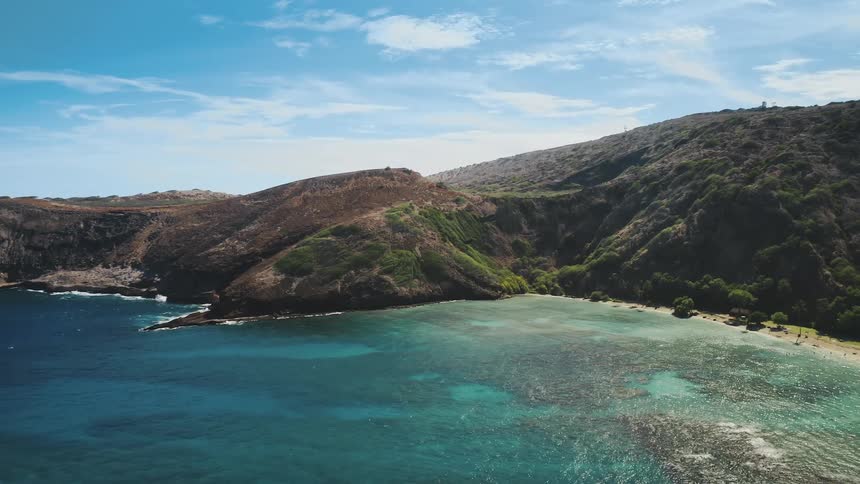 The ocean meets a scenic coastline that is surrounded by vegetation covered mountains