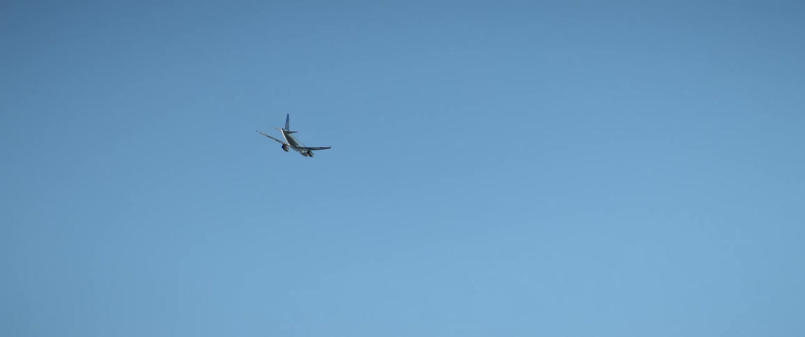 A small airplane flies through clear blue skies