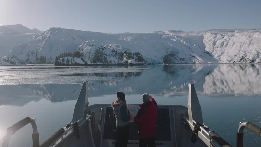 Men ride on a boat on a snowy mountain lake