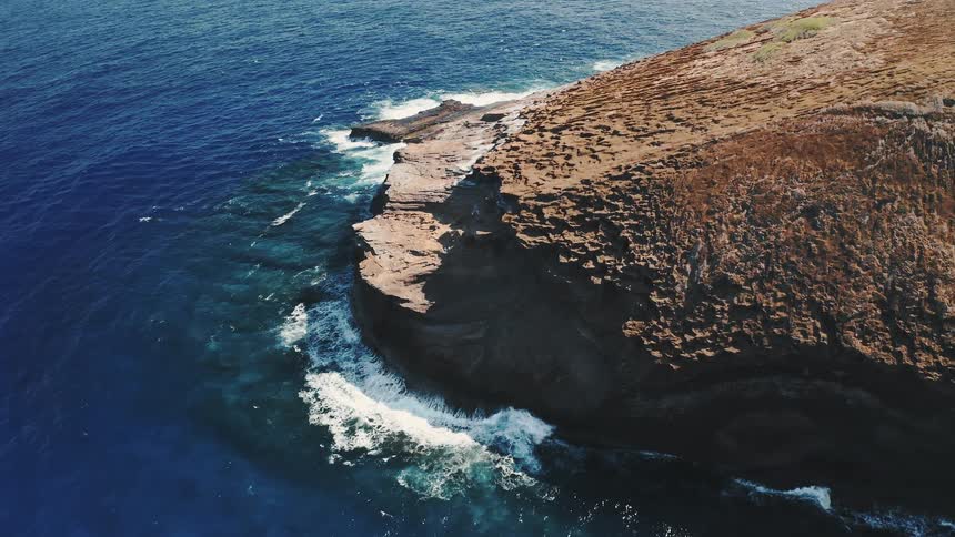 Aerial view of the jagged cliffs on a promontory near the clear blue ocean waters
