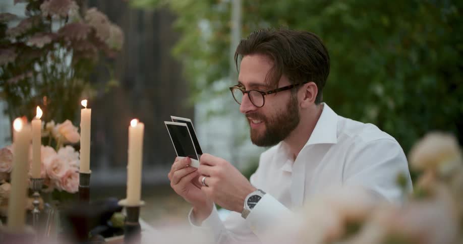 A man is looking at polaroid pictures