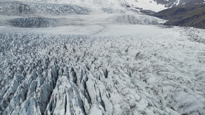 A dusting of snow covers the ground and side of a mountain range