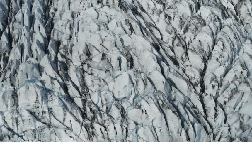 An aerial view of a large glacier reveals its jagged and treacherous surface