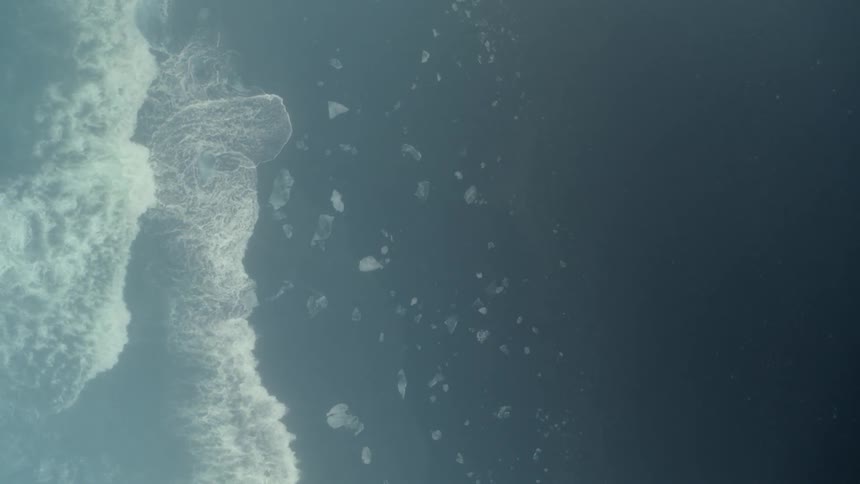 Overhead view of waves splashing and foaming as they roll in to shore