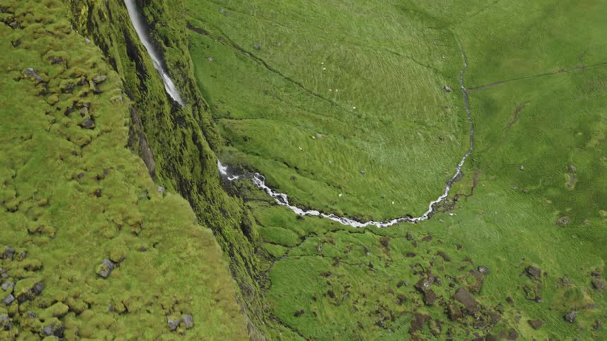 Aerial view of waterfall cascading down green mountainside