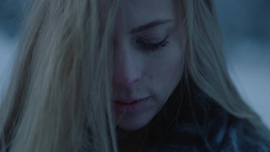 A woman is looking down as her hair blows across her face