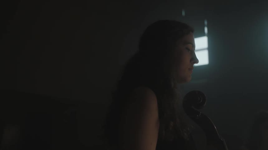 A woman is holding an instrument in a dark room