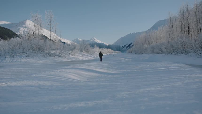 A man walks across a snowy hill