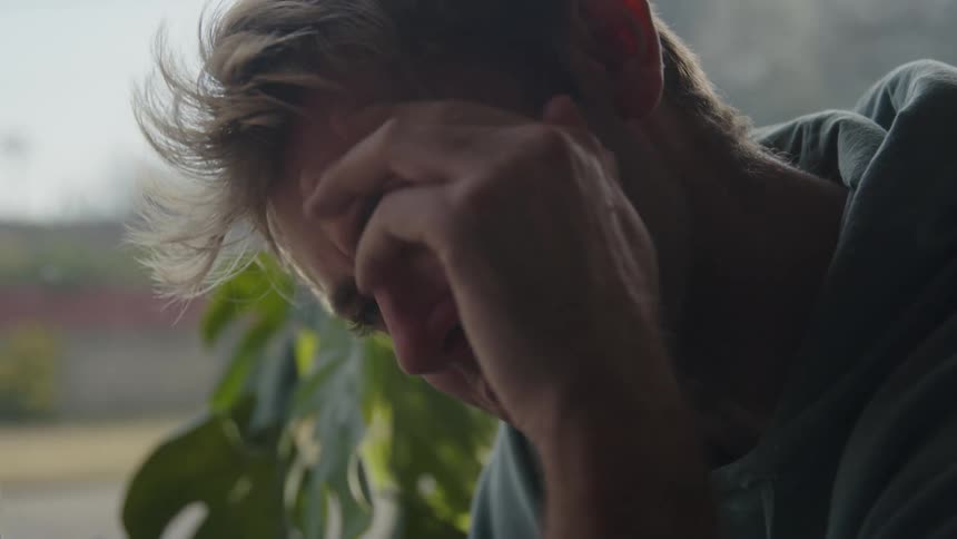 A mans face smiling with his hand on his face looking stressed