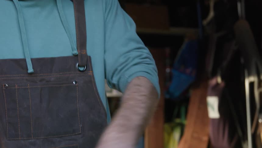 A man uses a small broom to sweep the top of a wooden table