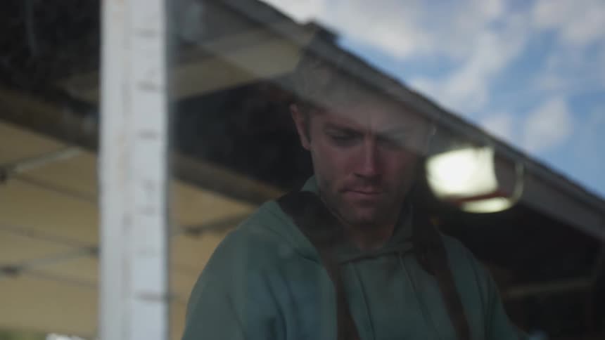 A man blows on a surface in his workshop