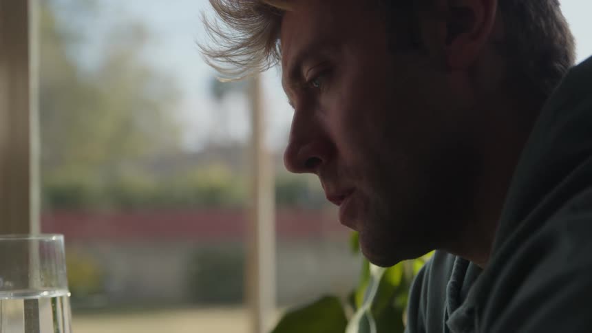 Close up of the face of a young blonde man eating breakfast at home in the morning