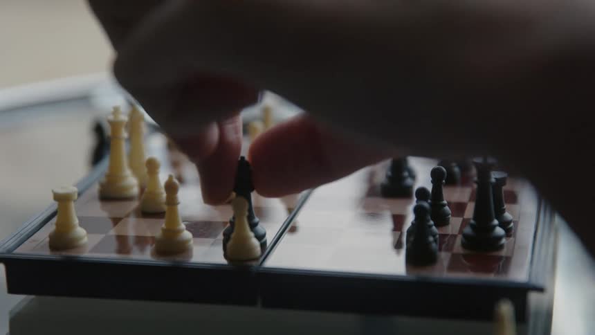 A person playing chess moves a piece and takes the opponents pawn