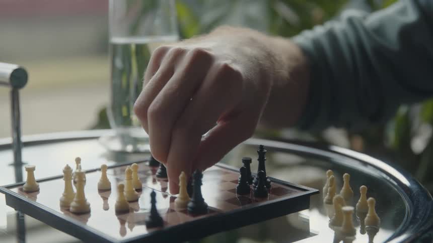 A man moving a chess piece on a chessboard