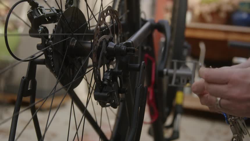 A man uses a socket wrench to fix his bicycle